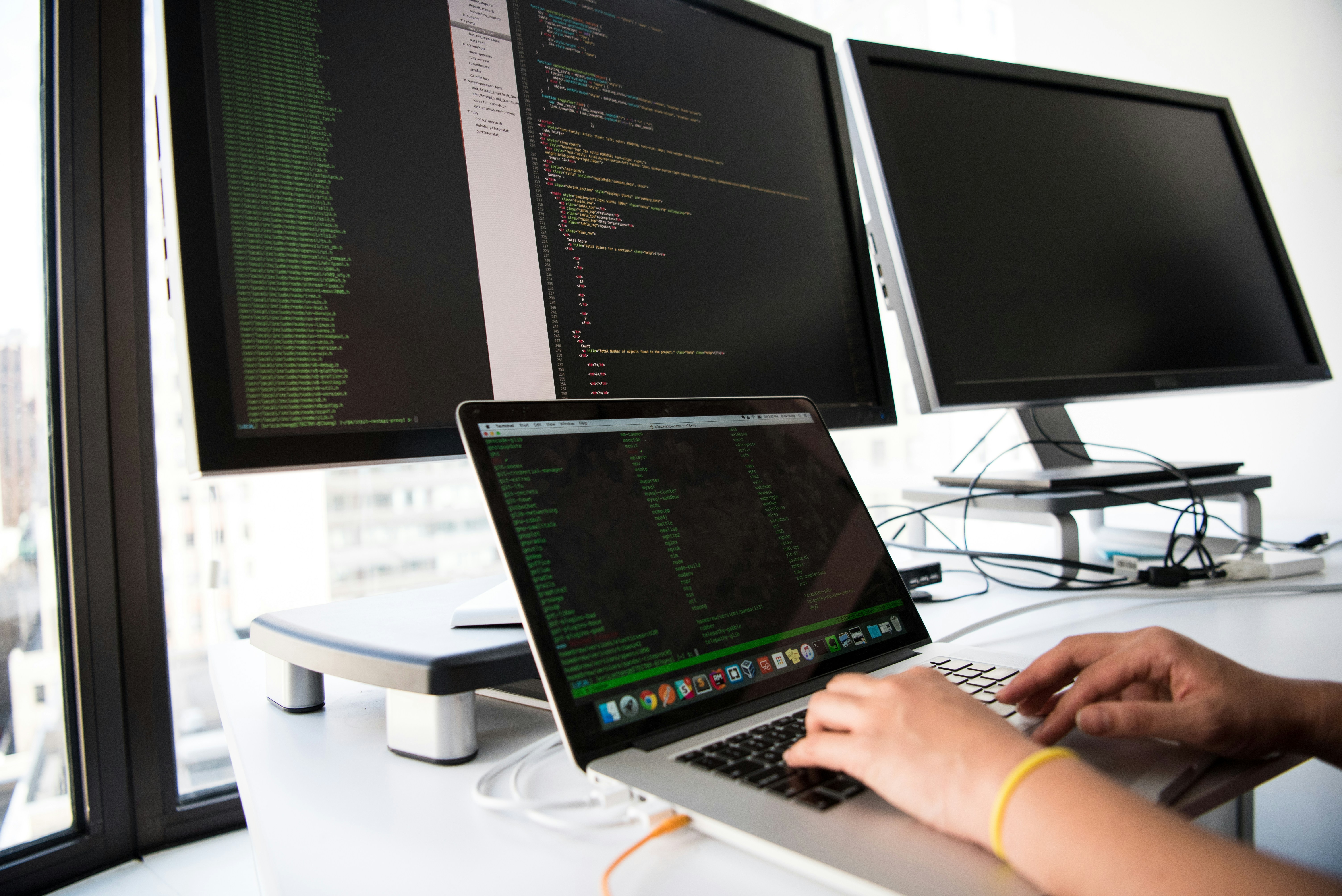 Meerdere schermen met code-editor in moderne werkruimte